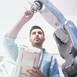 Männlicher Ingenieur wartet Roboterarm im Labor