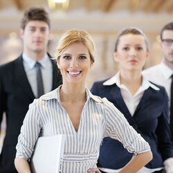 Geschäftsfrau steht mit ihren Mitarbeitern in einem Büro-Konferenzraum