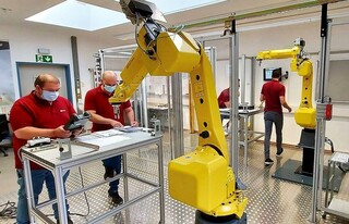 Mitarbeiter arbeiten an einem Roboter Mitarbeiter arbeiten an einem Roboter