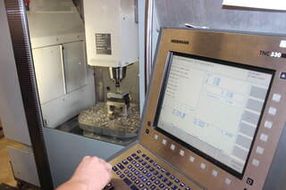 Person bedient eine Metallverarbeitungsmaschine über einen Computer Person bedient eine Metallverarbeitungsmaschine über einen Computer